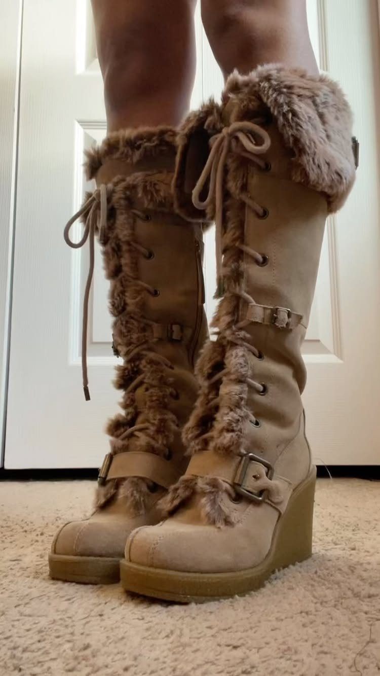 Tan suede wedge boots with faux-fur trim and buckles on a person.