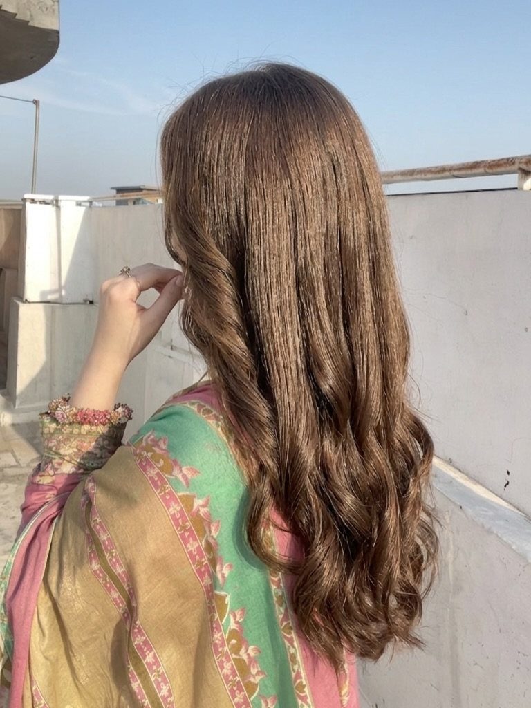 Long light brown wavy hair on a woman wearing a colorful patterned dress.