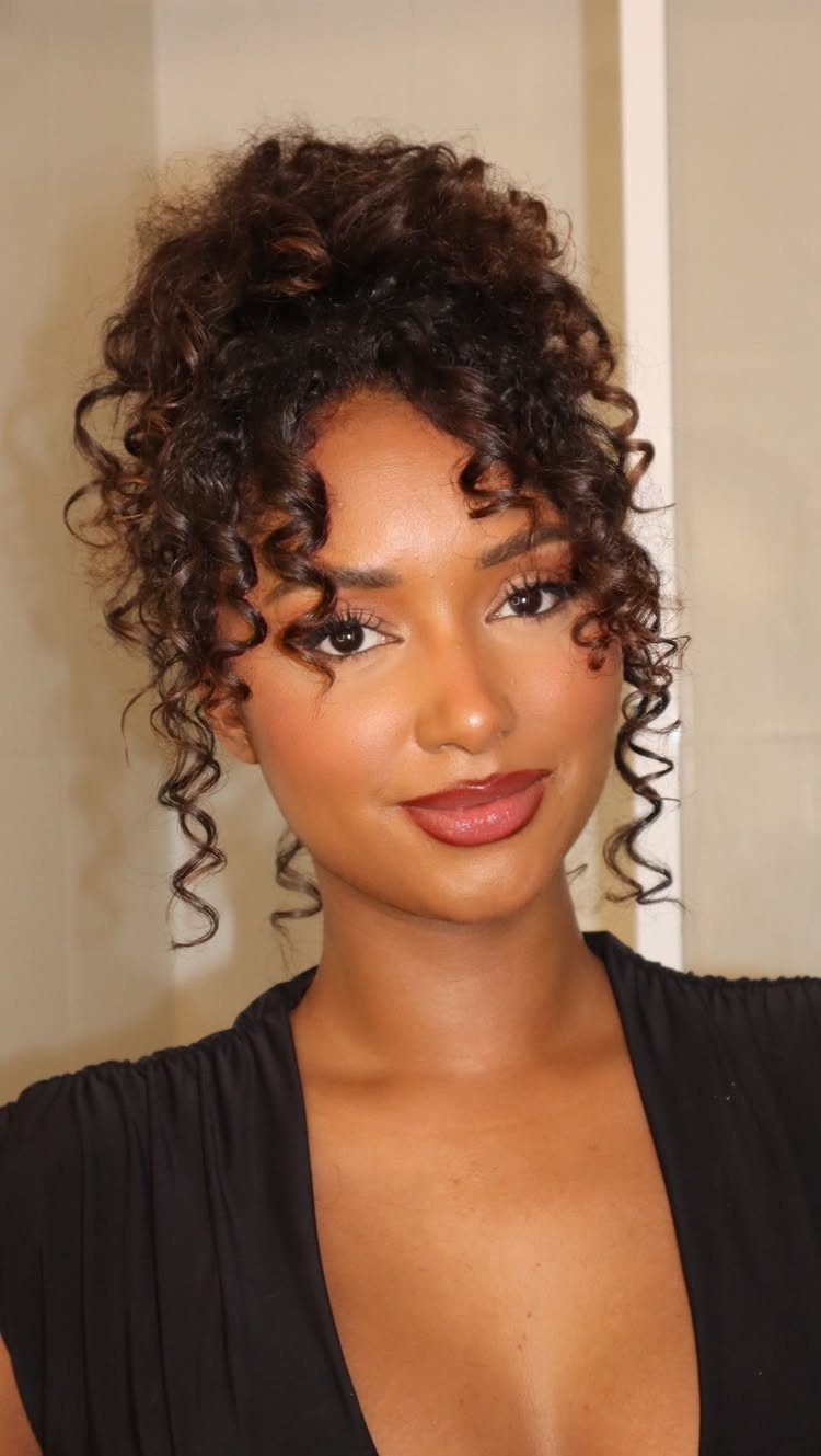 Woman with dark brown curly hair in an updo with face-framing ringlets.