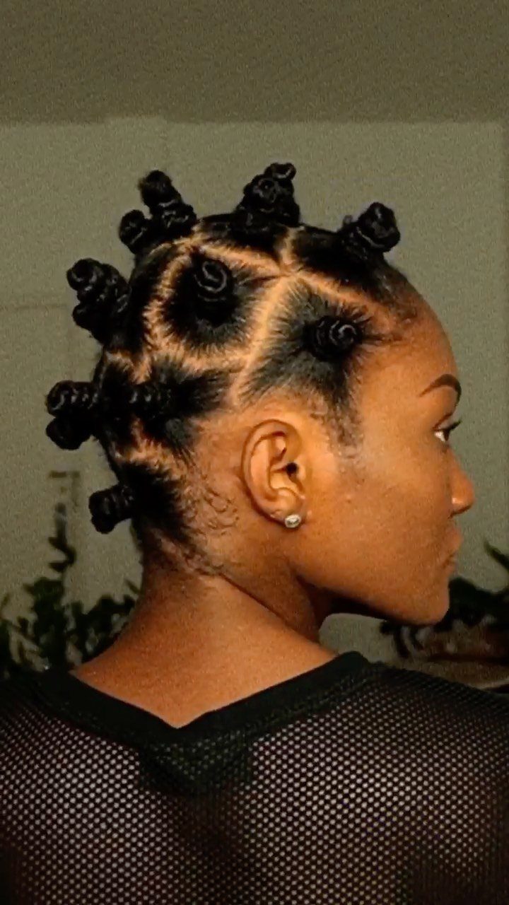 Black woman with hair styled in small, coiled Bantu knots in side profile