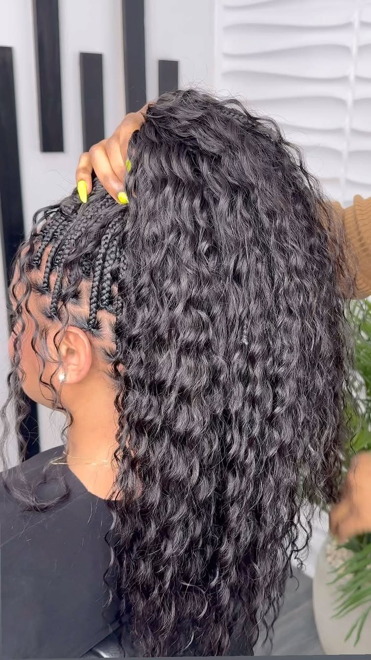 Long curly black hair with small braids styled along the side of the head.