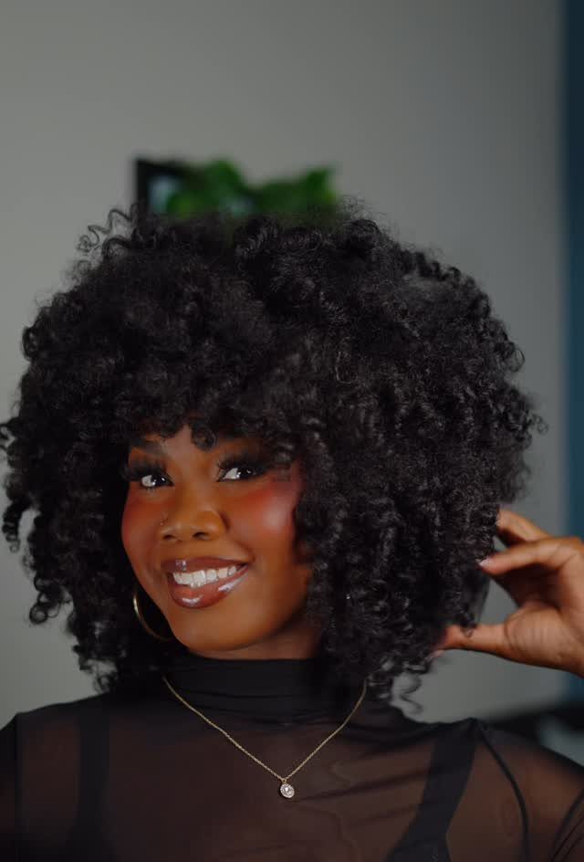 Woman with a voluminous curly black bob haircut smiling for a portrait.