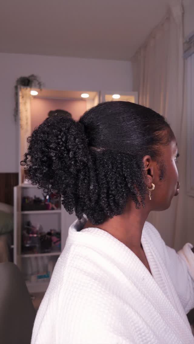 Woman with curly black hair styled in a half up half down ponytail