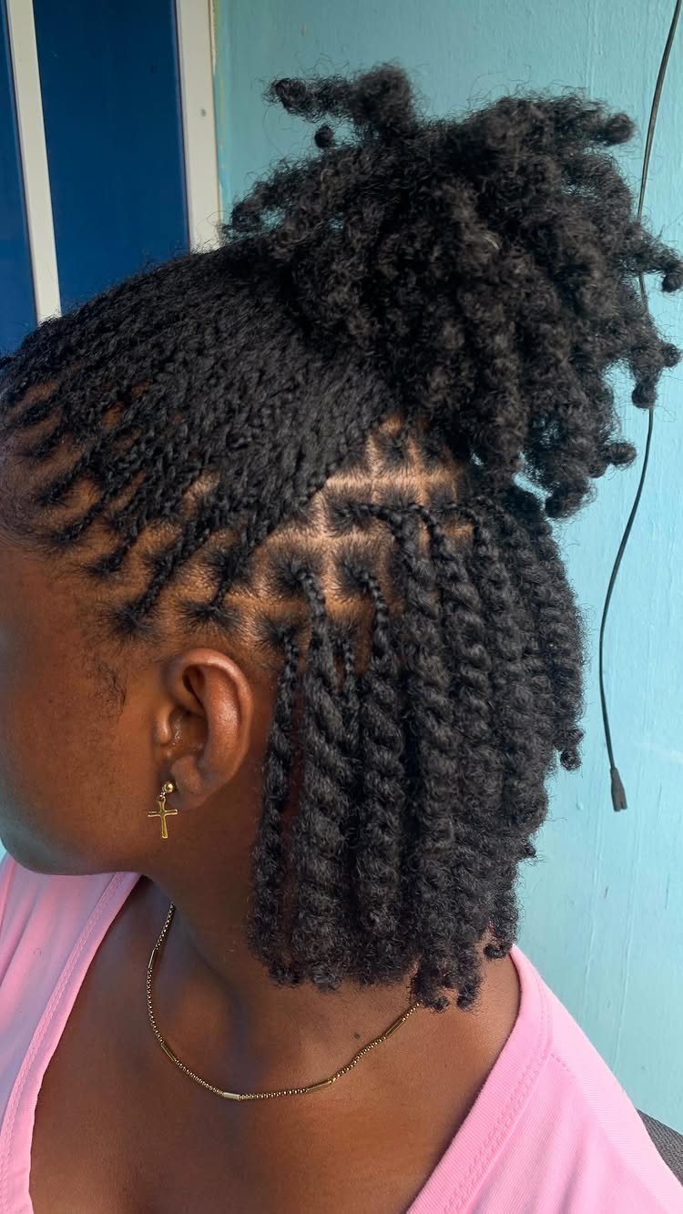 Person with black hair styled in twists and a high curly puff.