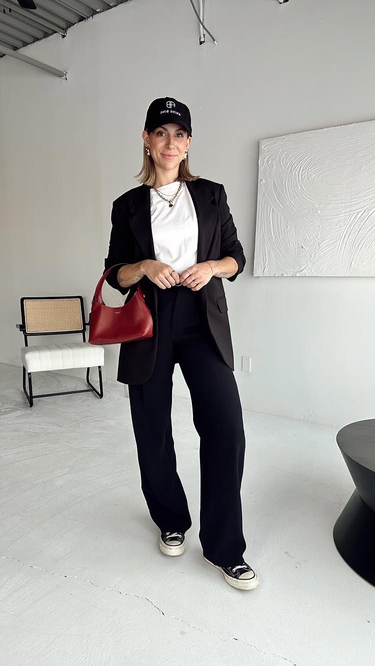 Woman wearing a black blazer and wide-leg trousers with a red handbag