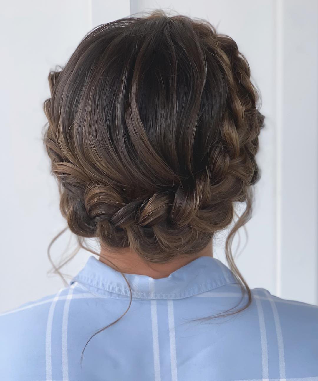 Brown hair styled in a thick braided crown updo gathered at the nape.