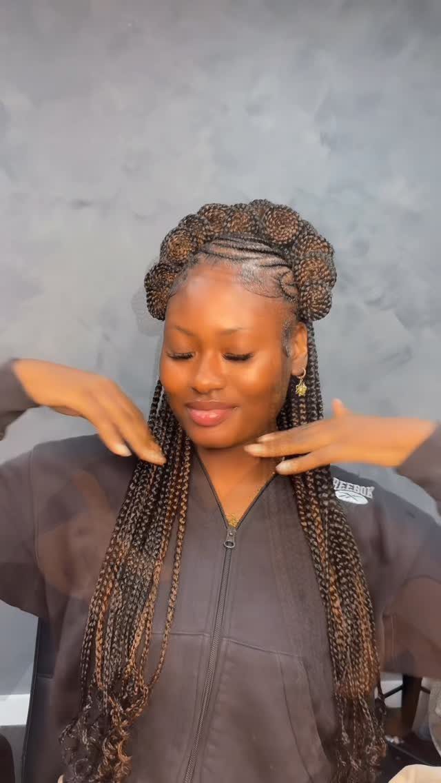 Woman with brown braids styled in a crown wrap around her head.