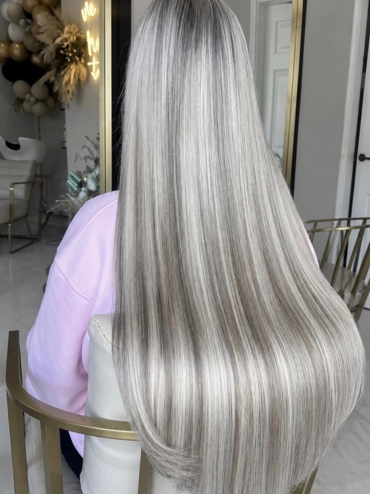 Long straight icy ash blonde hair with dark roots on a person.