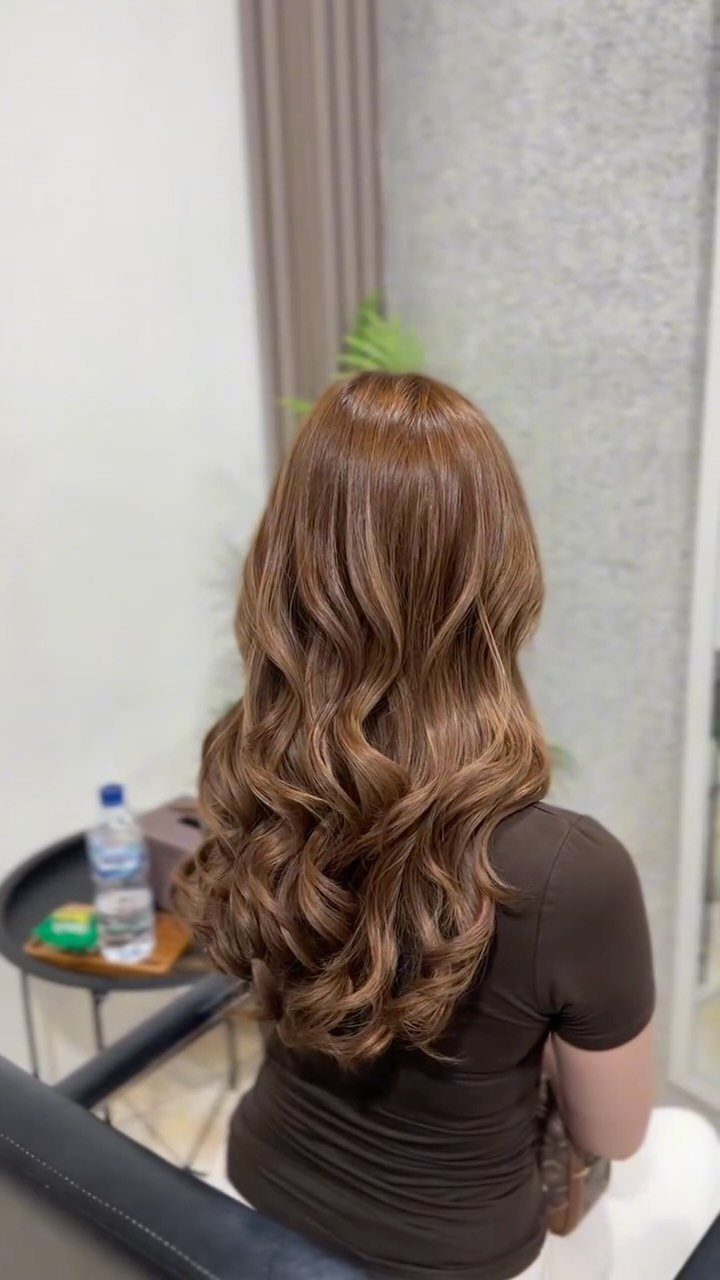 Long wavy light auburn brown hair styled in voluminous curls from behind.