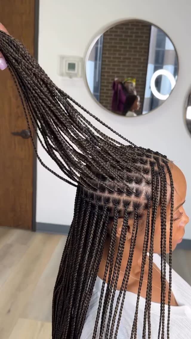 Person with long dark brown box braids held up to show scalp parting.