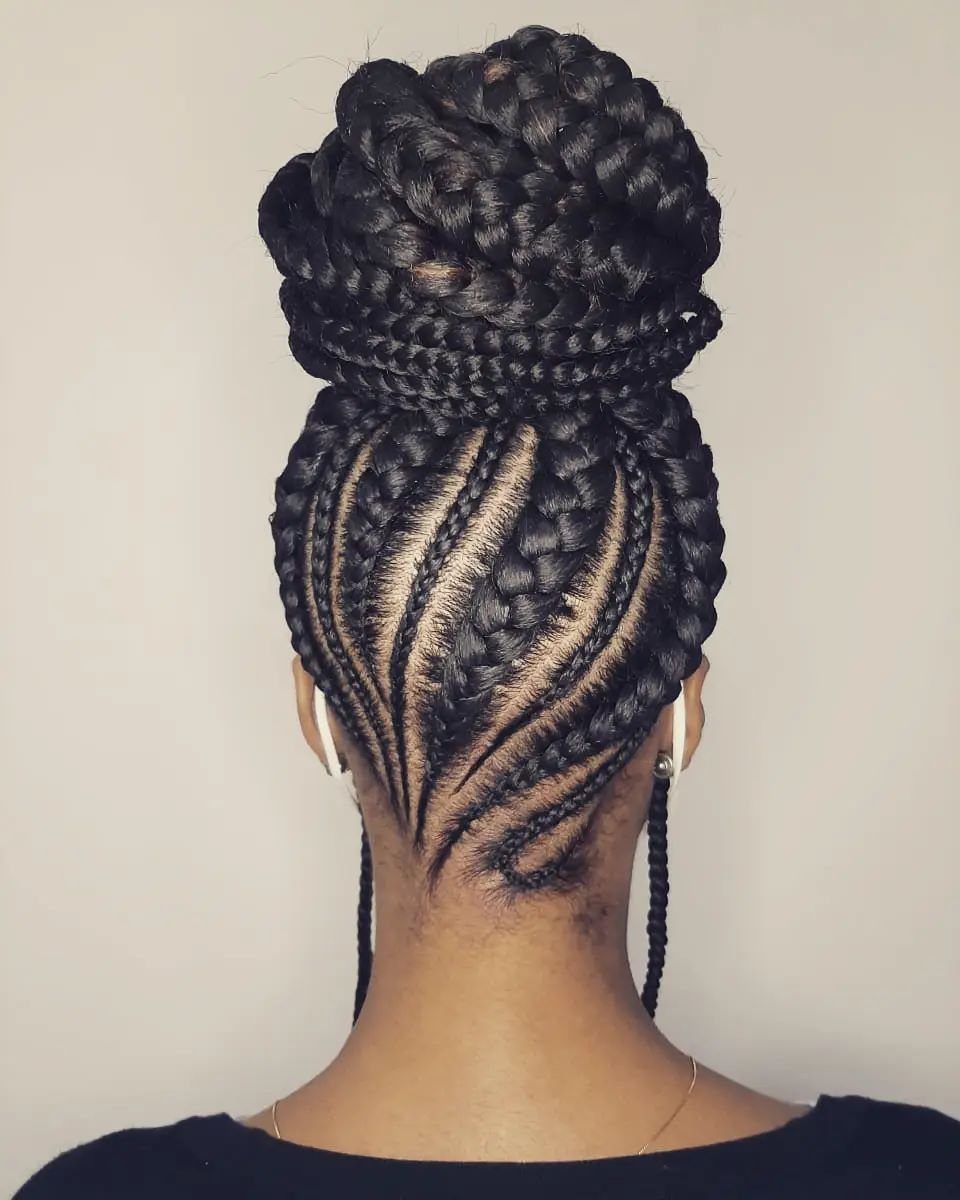 Intricate cornrow braids gathered into a large, textured braided top knot bun.
