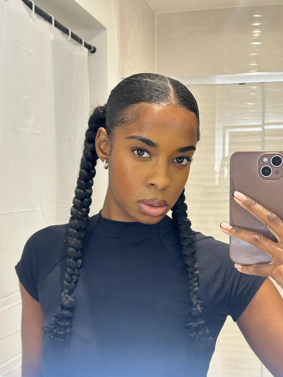 Woman with dark skin wearing black t-shirt and hair in two long braids.