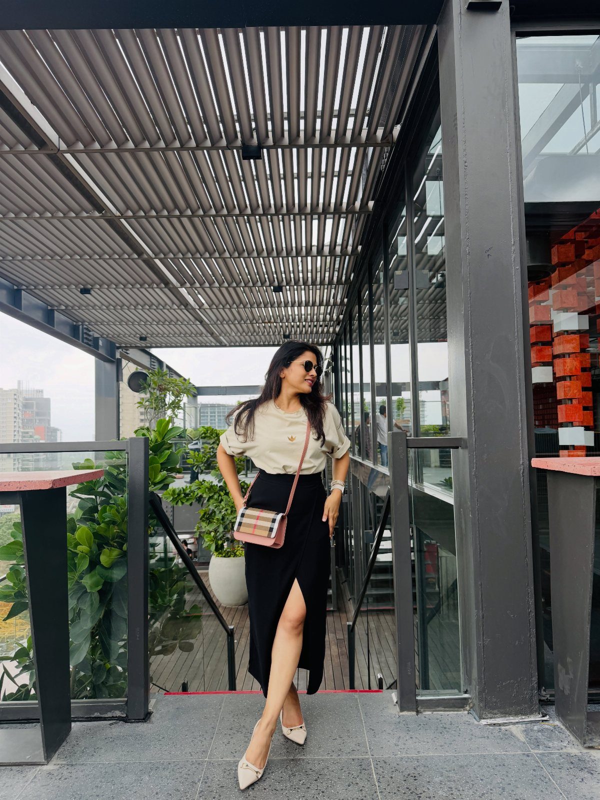 Woman wearing a cream t-shirt and black maxi skirt on a modern terrace