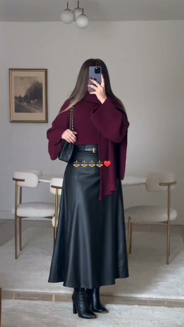 Person wearing a burgundy oversized sweater and long black leather skirt with boots.