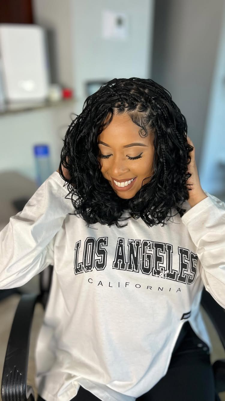 Woman with a black boho bob braid hairstyle and curly ends smiling.