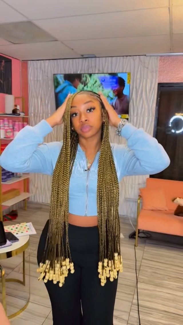 Woman with long golden-brown braids featuring decorative wooden beads at the ends.