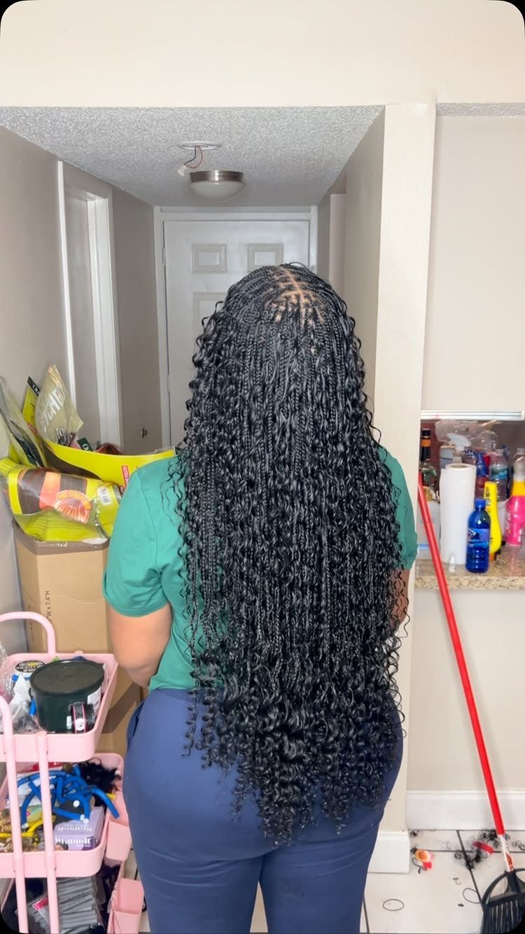 Long black boho braids with curly tendrils and spiral ends on a woman.