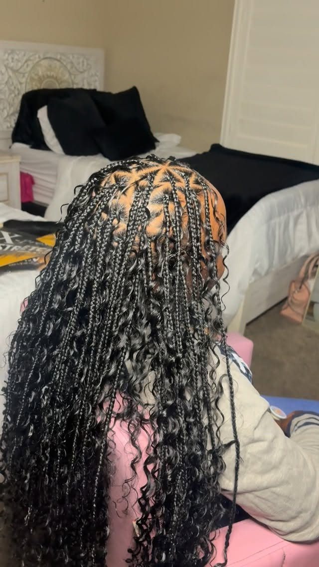 Long black boho braids with curly ends and distinct triangle parting on scalp.