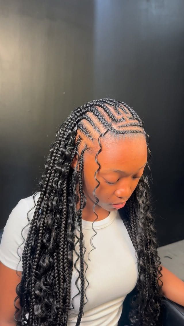 Woman with long black boho knotless braids and curly tendrils with geometric partings.
