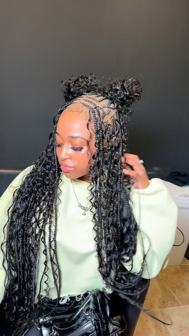 Woman with long black goddess box braids and curly tendrils in double buns.