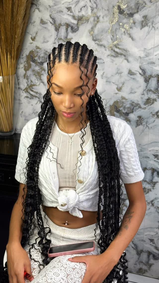 Woman with long black boho braids and curly ends wearing white clothing.