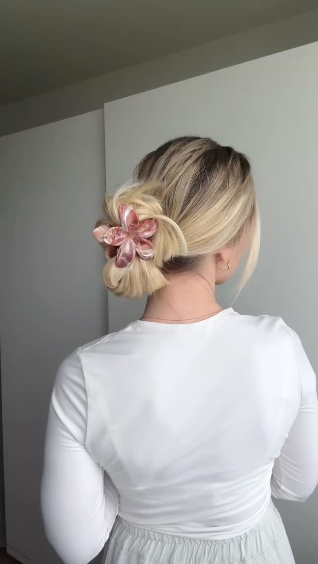 16 Bun Hairstyles for Homecoming: Updos, Braids and More 10 Blonde hair styled in a low bun with a pink floral hair clip
