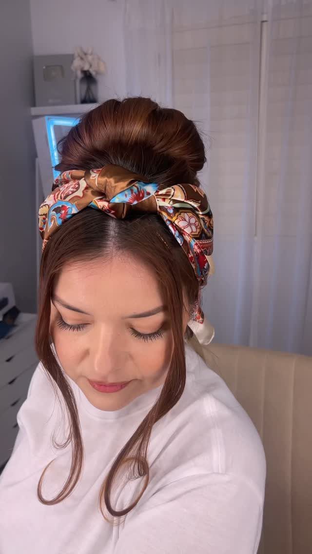16 Bun Hairstyles for Homecoming: Updos, Braids and More 12 Woman with a high brown hair bun and a patterned silk scarf accessory.