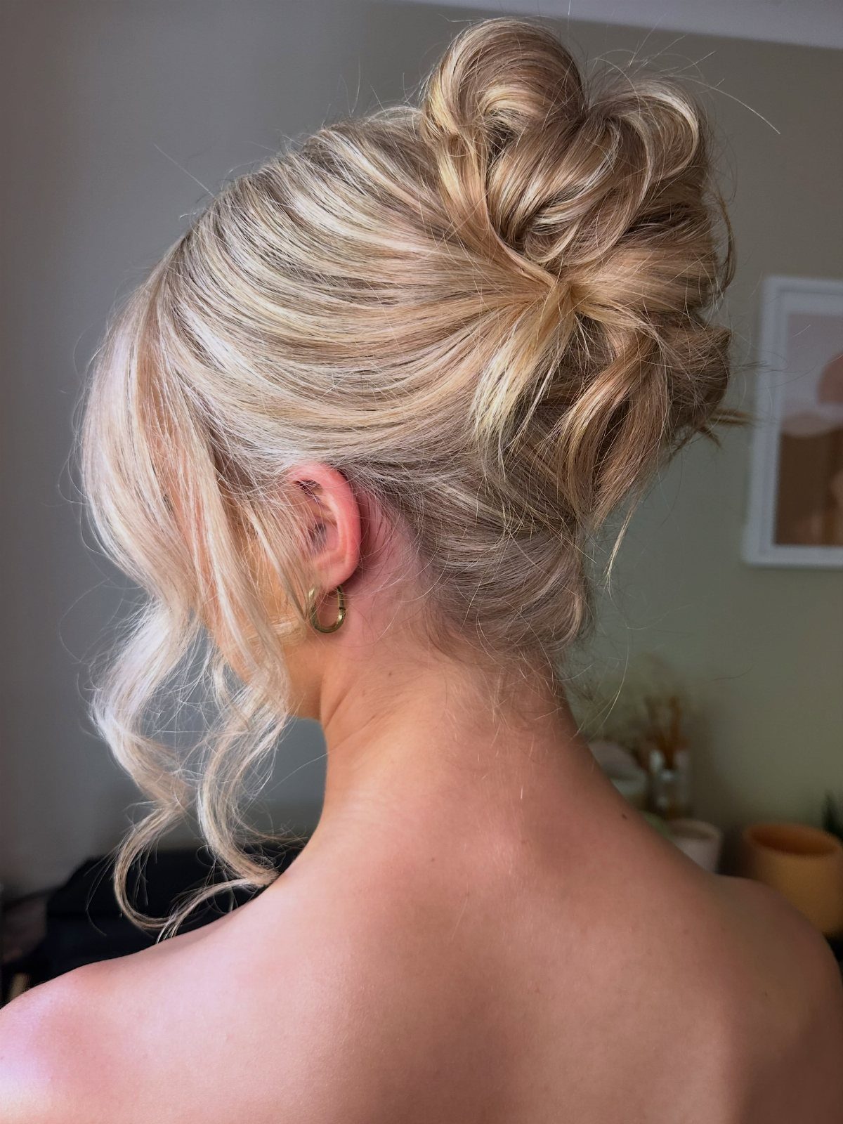 16 Bun Hairstyles for Homecoming: Updos, Braids and More 11 Blonde hair styled in a high messy bun with loose curled tendrils.