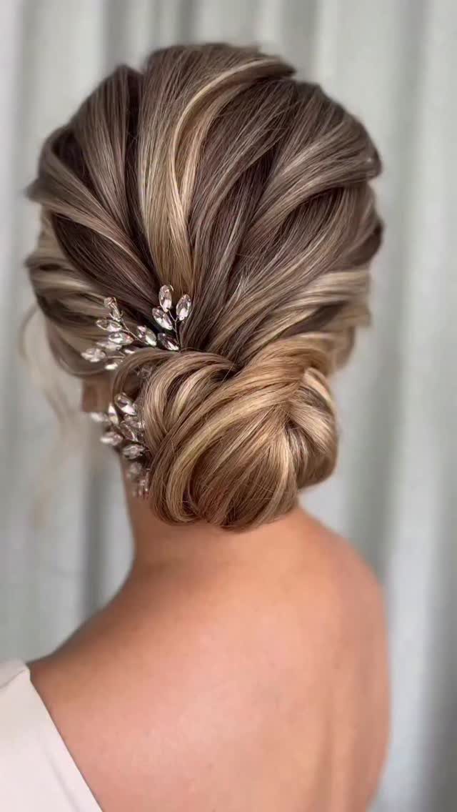 16 Bun Hairstyles for Homecoming: Updos, Braids and More 14 Intricate blonde low bun hairstyle with a sparkling silver floral hair accessory.