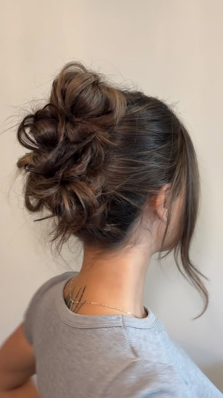 16 Bun Hairstyles for Homecoming: Updos, Braids and More 3 Brown hair styled in a voluminous loose updo with curled, textured strands.