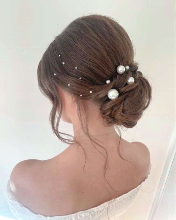 16 Bun Hairstyles for Homecoming: Updos, Braids and More 5 Brown hair styled in a low textured bun with decorative pearl hair pins.