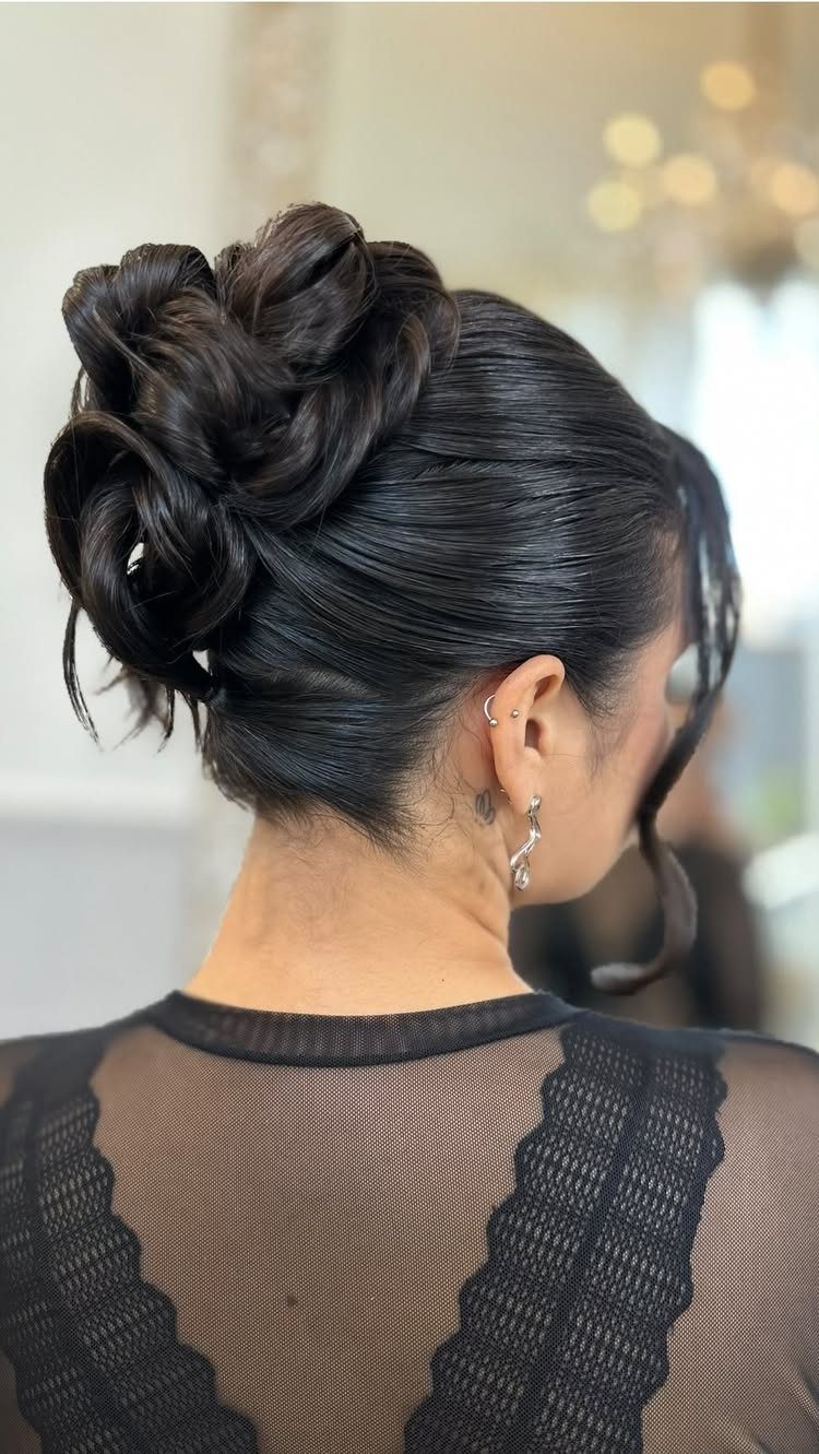 16 Bun Hairstyles for Homecoming: Updos, Braids and More 4 Dark hair styled in a voluminous, sleek updo bun from a back view.