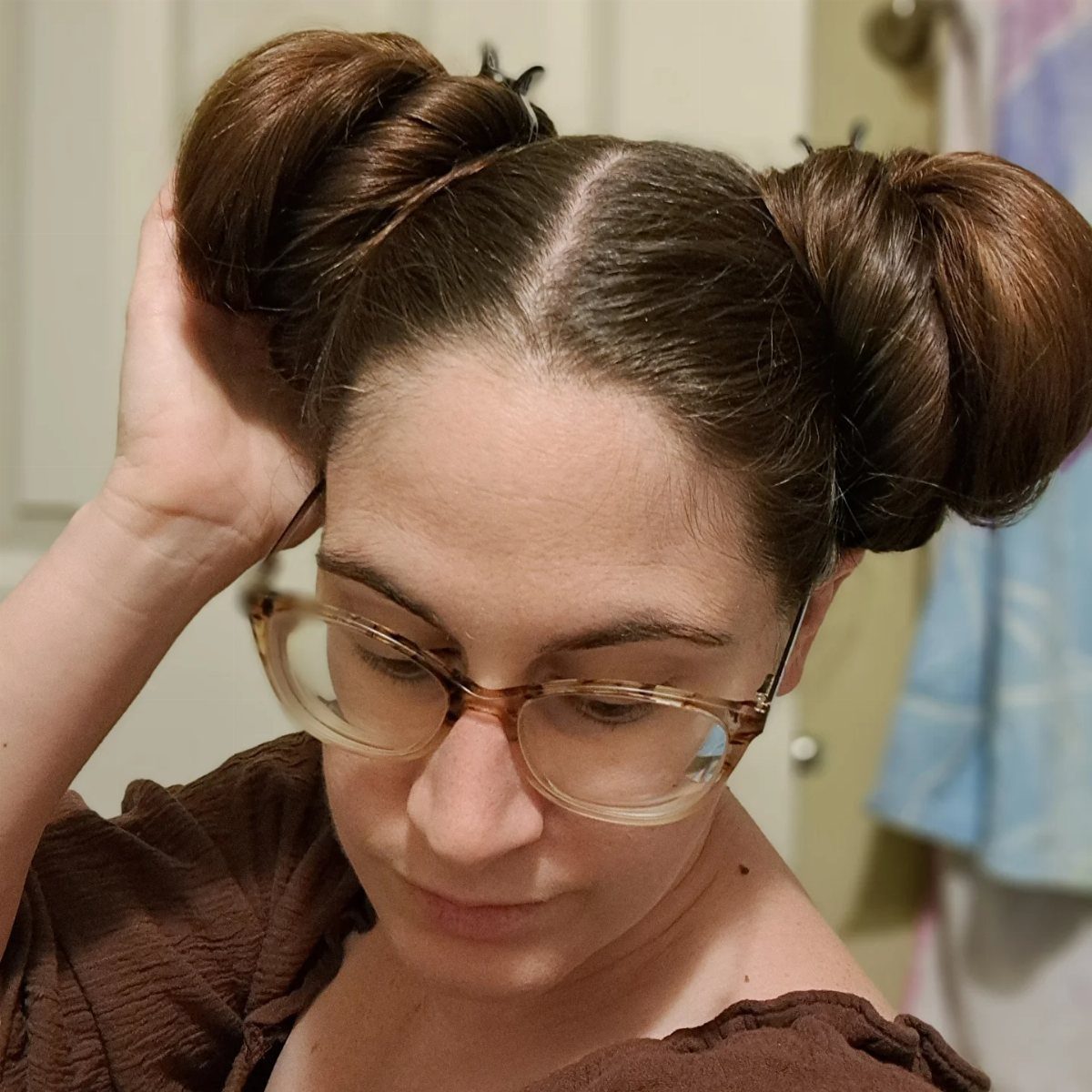 16 Bun Hairstyles for Homecoming: Updos, Braids and More 7 Woman with brown hair styled in two high space buns wearing glasses.