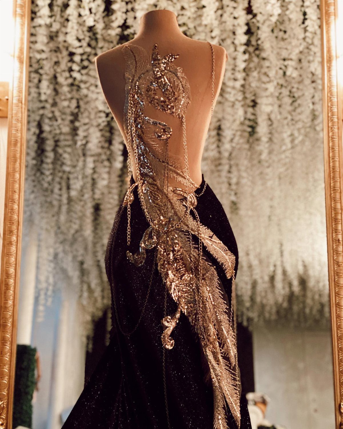 Celaena Sardothien Dresses: 10 Gown Ideas from the Books 8 Black evening gown on a mannequin with intricate gold sequin embroidery on the back.