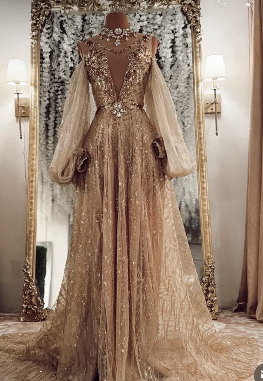 Celaena Sardothien Dresses: 10 Gown Ideas from the Books 2 Champagne off-the-shoulder gown with gold embroidery and voluminous sleeves on a mannequin.