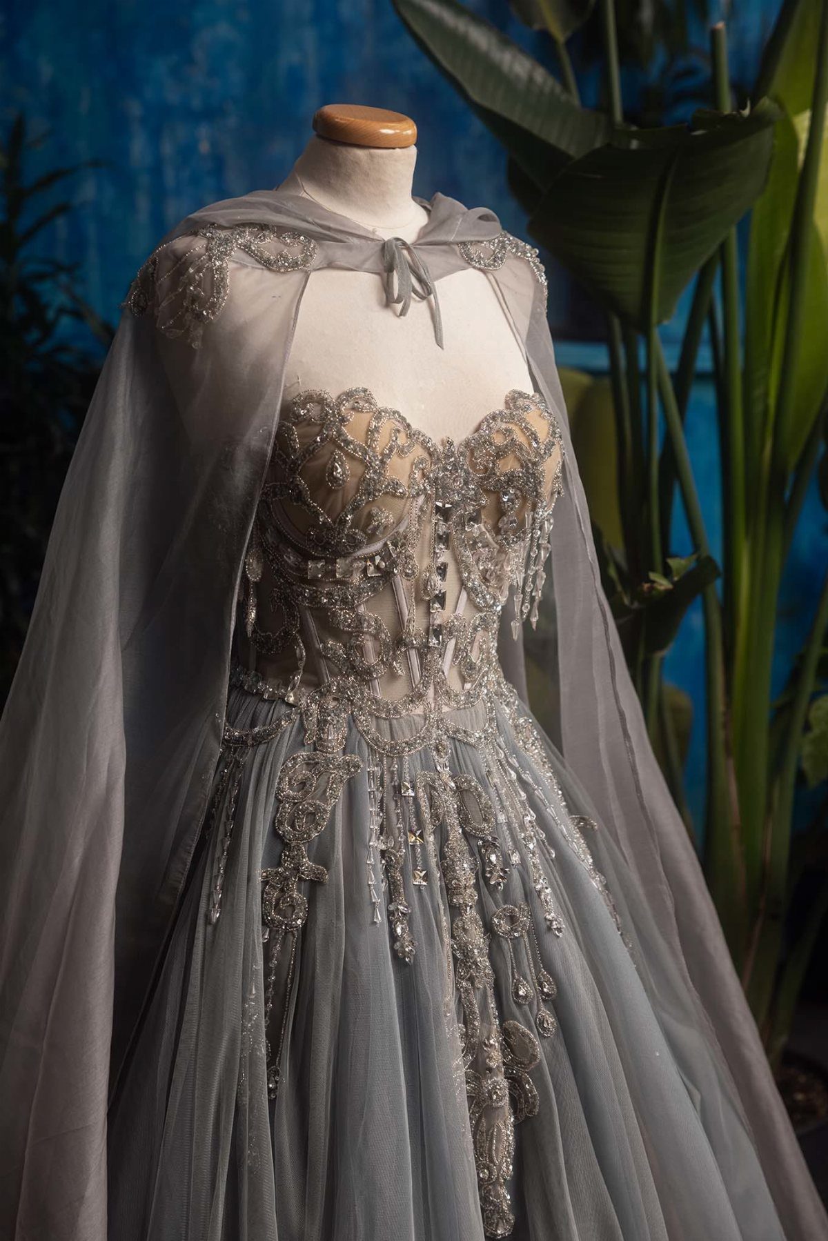 Celaena Sardothien Dresses: 10 Gown Ideas from the Books 1 Silver-grey tulle gown with metallic embroidery and a sheer cape on a mannequin.