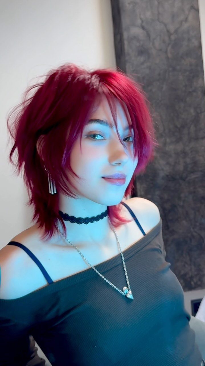 Cherry Red Hair Aesthetic: 7 Ideas for Every Length 7 Person with vibrant cherry red shaggy hair wearing a black off-the-shoulder top.