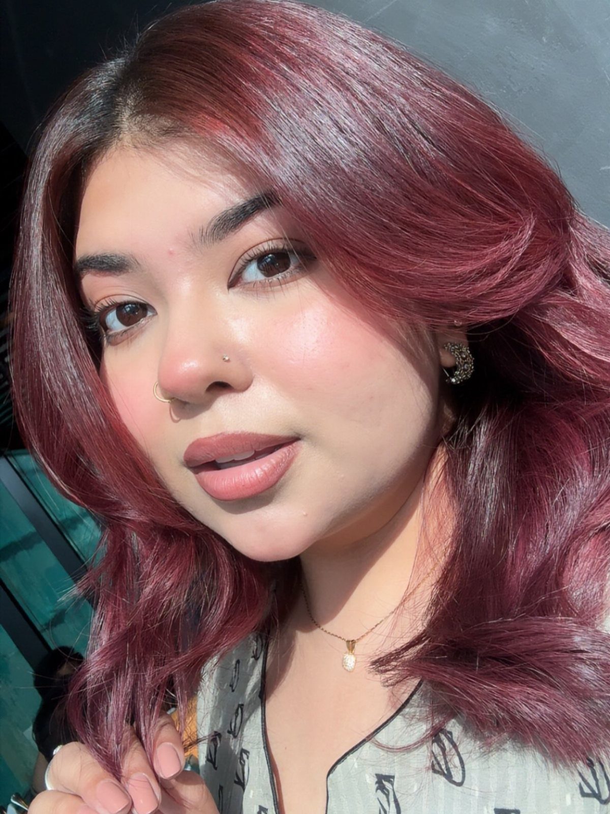 Cherry Red Hair Aesthetic: 7 Ideas for Every Length 1 Woman with long, wavy cherry red hair wearing a patterned top and necklace.
