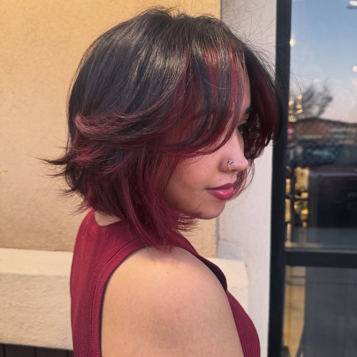 Cherry Red Hair Aesthetic: 7 Ideas for Every Length 3 Woman with a short cherry red layered bob haircut and burgundy top.