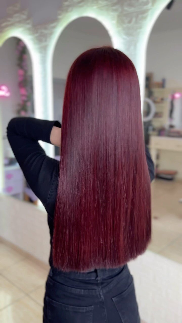 Cherry Red Hair Aesthetic: 7 Ideas for Every Length 6 Woman with long straight cherry red hair wearing black clothing in a bright room