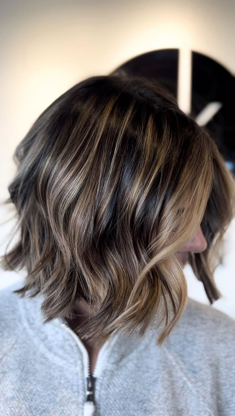 Short wavy bob haircut with dark brown base and caramel highlights.