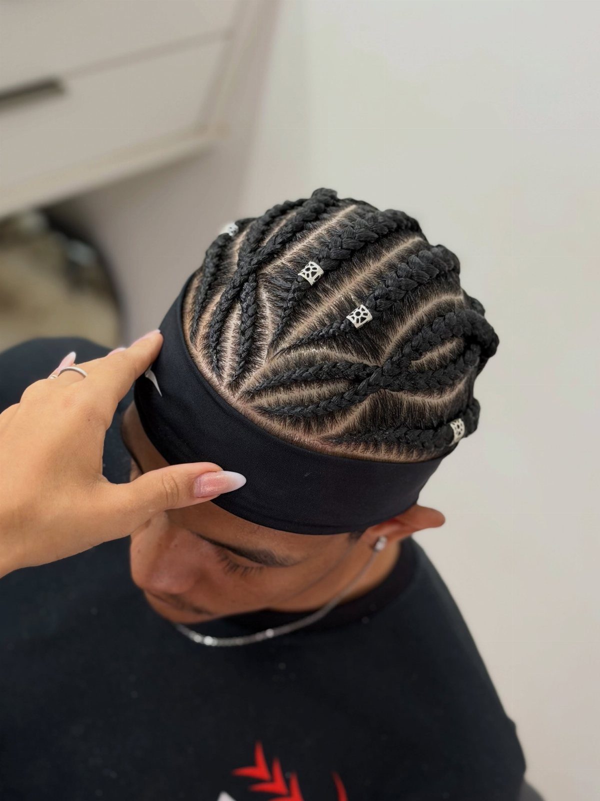 Man with intricate cornrow braids decorated with silver beads and a black headband