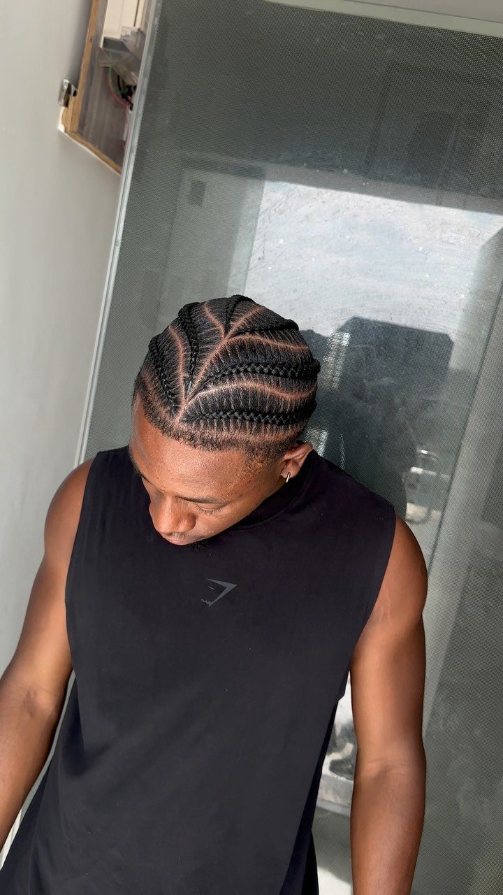 Man with symmetrical curved cornrow braids and a clean hairline wearing black shirt