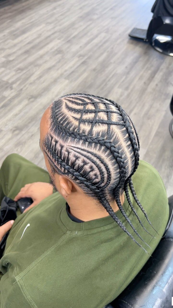 Man with intricate geometric cornrow braids viewed from above in a salon.