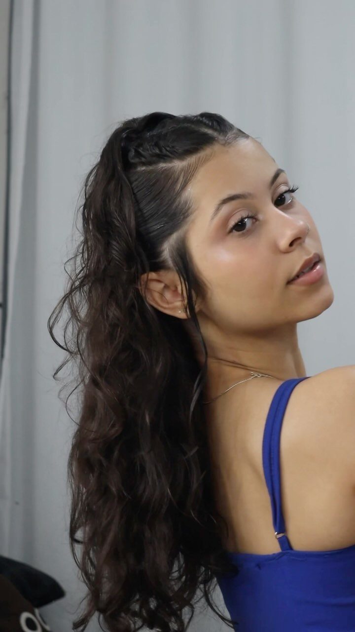 13 Curly Hair Half Up Styles with Braids, Twists and Puffs 12 Woman with long dark curly hair in a braided half-up hairstyle wearing blue.