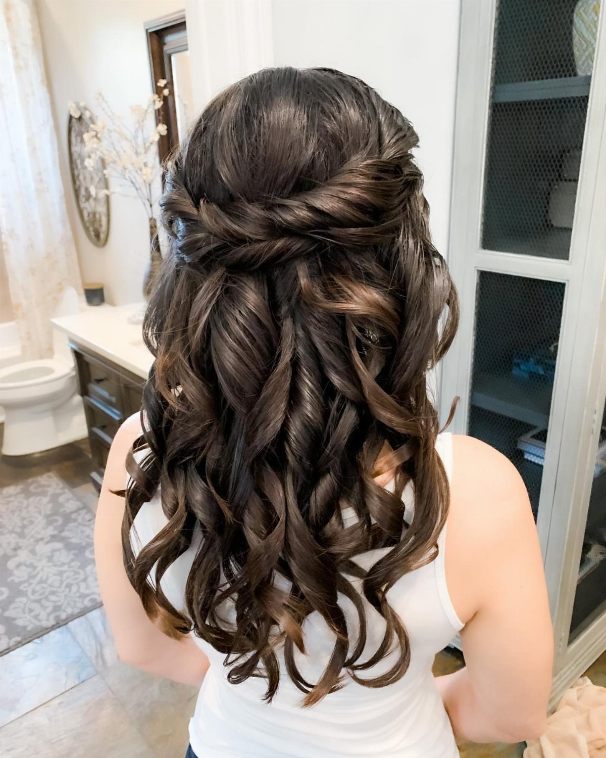 13 Curly Hair Half Up Styles with Braids, Twists and Puffs 5 Curly brown hair styled in a half-updo with a twisted braided back section.