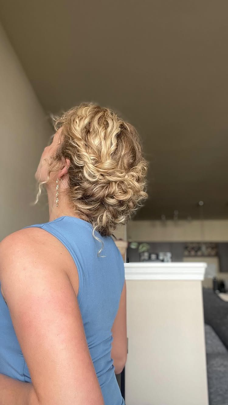 Blonde curly hair styled in a casual loose updo from a side profile.