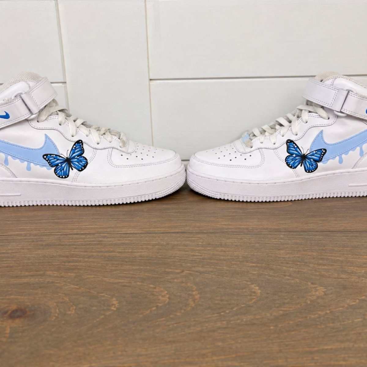 Custom Nike High Tops: 5 Ideas for Your Next Pair 4 White Nike Air Force 1 high-tops with blue drip accents and butterfly decals.