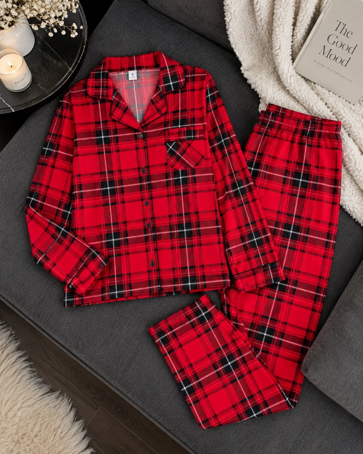 Red and black plaid flannel pajama set laid on a grey sofa.