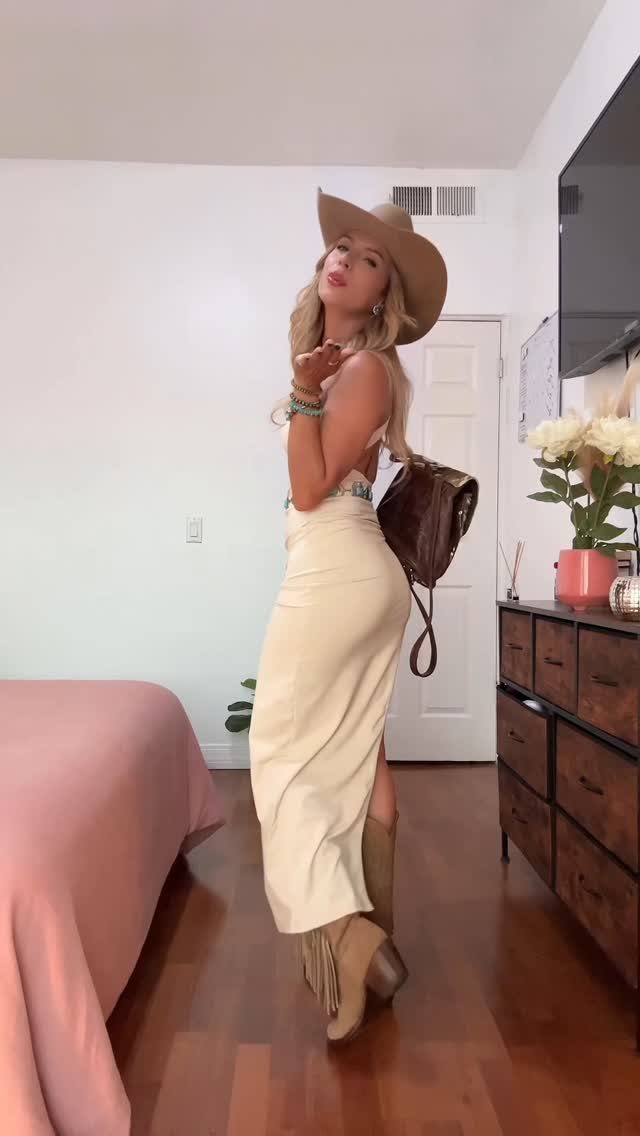 9 Cute Cowboy Outfits with Boots, Denim and Western Flair 9 Woman in tan cowboy hat and cream skirt posing in a bedroom